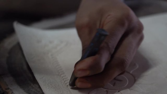Indian artisan makes embossed pattern on the leather for the book cover, in a traditional workshop in city Udaipur, Rajasthan, India, close up