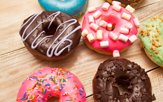 Many delicious donuts on the wooden table