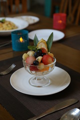 fruits ice cream on white plate with red candle and spoon
