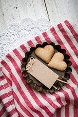 Liebe und Backen - Herz Kekse mit Anhänger in Backförmchen auf gestreiften Küchentuch