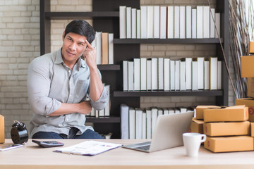 Happy young Asian man at office of his business online shopping.  