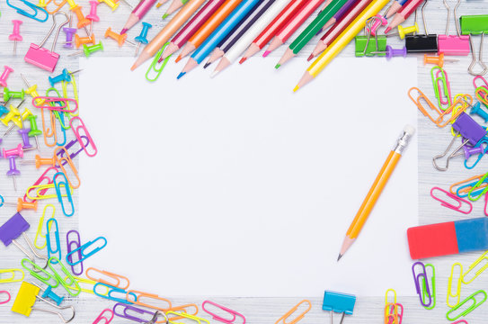 around the blank sheet of paper scattered colored paper clips, stationery and a simple pencil for writing