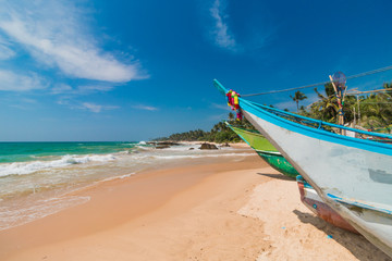Untouched tropical beach with palms and fishing boats in Sri-Lanka.  Fishing boats stand in Ambalangoda small harbor. 
