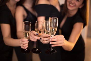 Cheers! Group of people cheering with champagne flutes with holiday lights on background with copy space.