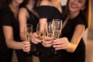 Cheers! Group of people cheering with champagne flutes with holiday lights on background with copy space.