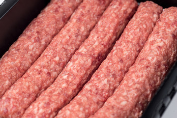 Packed raw sausages in black plastic black tray