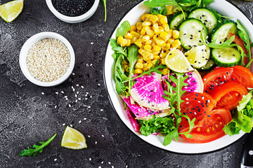 Vegan buddha bowl. Bowl with fresh raw vegetables - cucumber, tomato, watermelon radish, lettuce, arugula and corn. Fresh salad. Vegetarian food. Top view. Flat lay