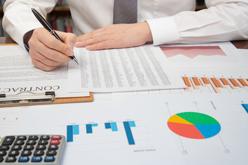 Workplace businessman. Contracts, charts, and graphs on the desk.