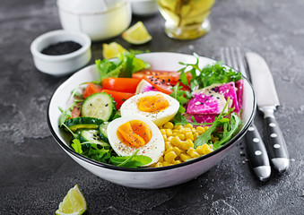 Fresh salad. Bowl with fresh raw vegetables - cucumber, tomato, watermelon radish, lettuce, arugula, corn and boiled egg. Healthy food. Vegetarian buddha bowl.