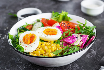 Fresh salad. Bowl with fresh raw vegetables - cucumber, tomato, watermelon radish, lettuce, arugula, corn and boiled egg. Healthy food. Vegetarian buddha bowl.