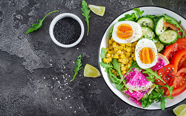 Fresh salad. Bowl with fresh raw vegetables - cucumber, tomato, watermelon radish, lettuce, arugula, corn and boiled egg. Healthy food. Vegetarian buddha bowl. Top view. Flat lay