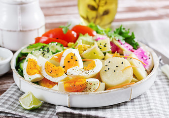 Fresh salad. Vegetarian buddha bowl. Bowl with boiled potato, cucumber, tomato, watermelon radish, lettuce, arugula, corn and boiled egg.  Healthy food.