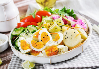 Fresh salad. Vegetarian buddha bowl. Bowl with boiled potato, cucumber, tomato, watermelon radish, lettuce, arugula, corn and boiled egg.  Healthy food.