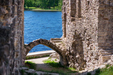 Ancient fortress close to the river or lake with arch entrance or gate to castle garden. 