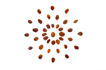 A collection of  brown raisins  lies in the shape of a circle or sun on an isolated white...