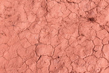 Dry cracked desert soil during drought - top down view, coral tone