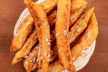 A closeup of traditional Spanish porras, a typical Madrid Sunday breakfast, shot from the top on a dark rustic wooden background