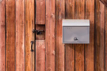 Grey mail box hanging on wooden wall