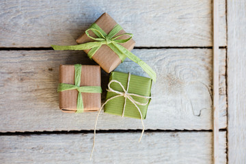 Geburtstag - Kleine Geschenke in hellgrün und Kraftpapier auf hellen Holz
