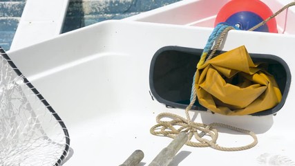 Interior of a small fishing boat deck, containing fishing net and protective waterproof oilskins.
