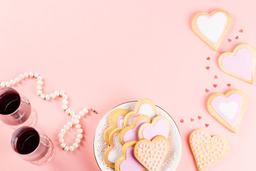 Happy Valentine's day greeting card with heart cookies, wine glasses and wine on pastel pink background.