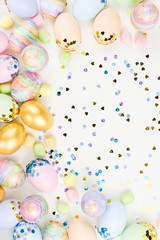 Festive Easter background with decorated eggs, flowers, candy and ribbons in pastel colors on white. Copy space