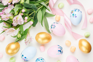 Festive Easter background with decorated eggs, flowers, candy and ribbons in pastel colors on white. Copy space