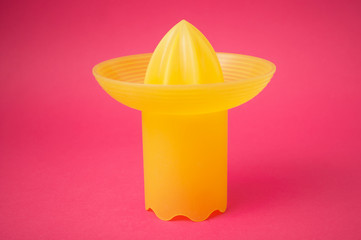 closeup of yellow fruit squeezer on pink background