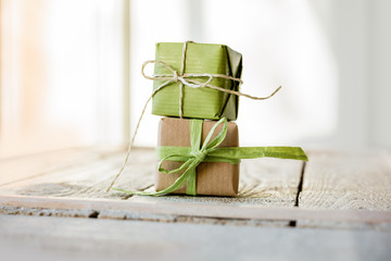Geburtstag - Kleine Geschenke in hellgrün und Kraftpapier auf hellen Holz gestapelt