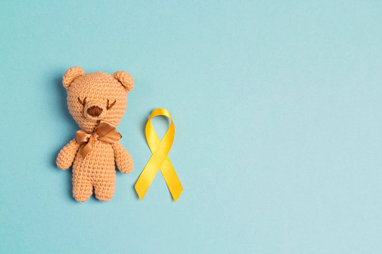 Children's toy with a Childhood Cancer Awareness Yellow Ribbon on blue background.