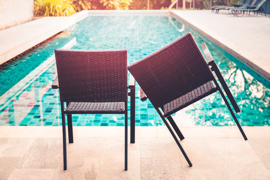 Conceptual coupel comfortable chair by swimming pool with sunlight.