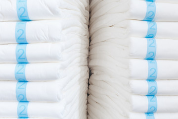 Stacks of adult diapers, closeup view. Health care for elderly and bedridden people with urinary incontinence