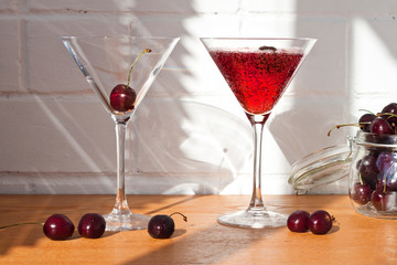 Cold alcoholic cocktail with cherry on the sunny table background