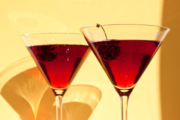 Red cocktail with cherry on yellow  background