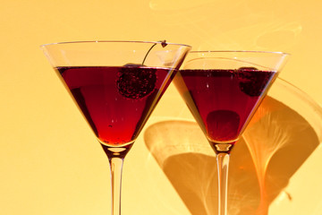 Red cocktail with cherry on yellow  background