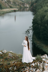 Fototapeta na wymiar Morning bride on a beautiful panoramic location. Girl in boudoir dress and cliffs.