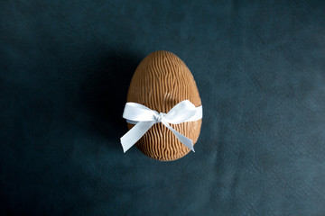 Chocolate egg with white ribbon. Symbol Happy Easter.