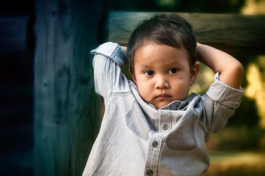 Young Toddler Boy That Looks Troubled, Worried, Or Expressing Anti Social Behavior While Holding His Head With His Arms.