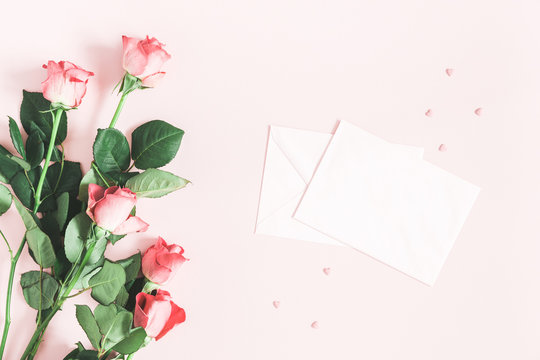 Flowers composition. Pink rose flowers, envelopes on pastel pink background. Valentines day, mothers day, womens day concept. Flat lay, top view, copy space
