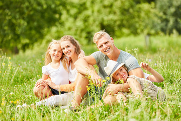 Familie sitzt entspannt in der grünen Natur