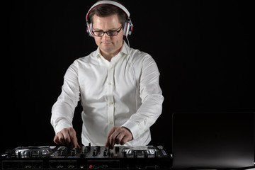 DJ hört Musik über Kopfhörer und mischt die Titel am Mischpult