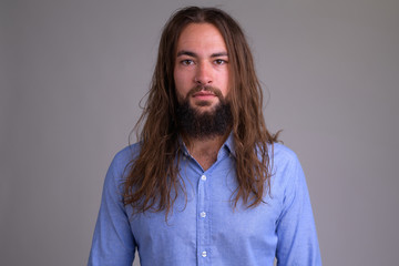 Portrait of young handsome bearded businessman with long hair