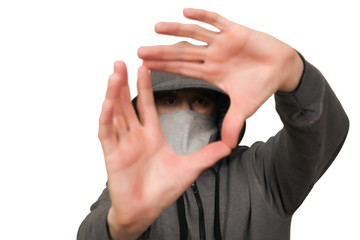 The man in a gray sports jacket and in a mask on a face shows gestures by hands