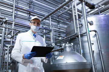 technologist taking necessary notes while standing at production department of dairy factory