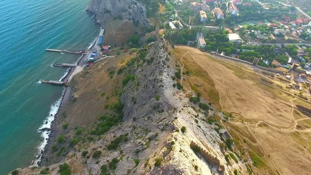 Consular castle and the fortification wall on mountain near coastline black sea. Aerial drone footage over Genoese fortress in Sudak, Crimea.