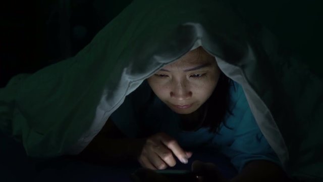 Asian woman play smartphone in the bed at night,Thailand people,Addict social media,Play internet all night,Lychnobite	