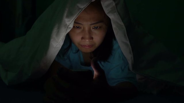 Asian woman play smartphone in the bed at night,Thailand people,Addict social media,Play internet all night,Lychnobite	