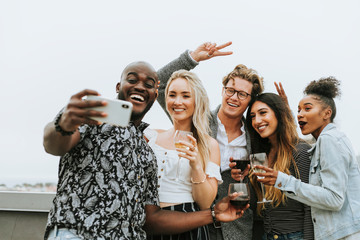 Diverse group of friends taking a selfie at a rooftop party