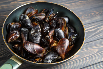 Mussels with parsley and garlic in wok pan on wooden table