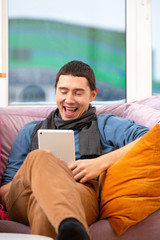Fototapeta premium Man sit on the couch and using a tablet computer